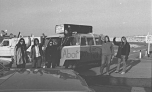 This photo of the Abortion Caravan during stop in Calgary features Cathy Walker standing in the door of the van, with Charlotte Bedard's truck and camper in the background.