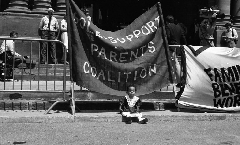 This is an undated photo of a protest held at Queen's Park showing banners of the Sole Support Parents Coalition.