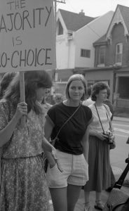 This photo of Beth McAuley and others is from an 1983 abortion rights rally organized in support of Dr. Henry Morgentaler and legalizing free-standing abortion clinics. It was held outside Dr. Morgentaler's clinic on Harbord Street in Toronto.