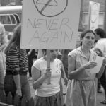 Placard at 1983 support rally outside the Morgentaler Clinic in Toronto shows a coat hanger and reads, "Never Again".