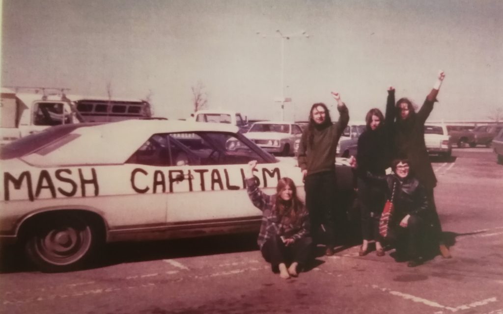 During a stop en route to Ottawa, members of the Abortion Caravan raise their fists for a photo alongside Betsy Wood's convertible with the slogan "Smash Capitalism" painted on the side panel.