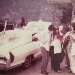 This photo taken was during a gas stop near Hope, British Columbia during Abortion Caravan's trip across Canada. Betsy Wood is on the left side of her convertible with an "On to Ottawa" sign fastened on the front. On the right side, from left to right: Dodie Weppler, Ellen Woodsworth, Gwen Hauser, and Bonnie Beckwoman.