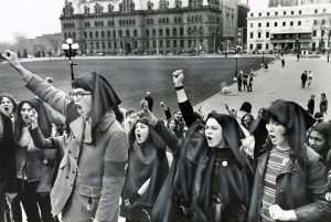 Women wearing headscarves and with raised fists gather on Parliament Hill during a May 11, 1970 protest for abortion rights. Inside the House of Commons, another group of women speaking from the galleries interrupted the session, forcing an adjournment until after they were removed.