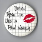 Undated button that says "Behind These Lips Lies a Real Woman"