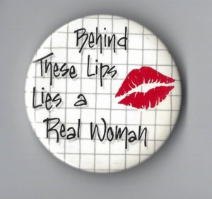 Undated button that says "Behind These Lips Lies a Real Woman"