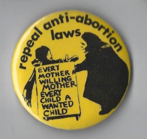 This undated button calls for the repeal of abortion laws so that every mother is a willing mother and every child a wanted child.