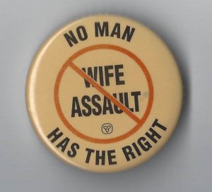 This undated button was produced by the Ontario government stating that there is no right allowing that allows a man to assault his wife.