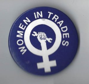 This button for women in trades features the woman symbol with an upraised fist holding a wrench.