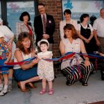 This 1996 photo is from the June 1st opening festivities for the CAW Oshawa Child Care Facilities. The first child enrolled is shown front/centre. Also taking part are child care centre workers and, in the back row (l to r) : unidentified man; Laurel Rothman, director of CAW childcare services; Jim Cameron of General Motors; Peggy Nash, assistant to CAW President; unidentifed woman; Dave Broadbent, CAW Local 222 secretary-treasurer; and Nancy Diamond, Oshawa Mayor. The photo is from the CAW Archives.