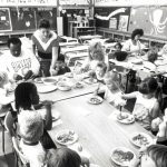 Staff and children are at mealtime in the CAW labour community childcare centre in Windsor. The Windsor Centre was opened in 1989 after the Canadian Auto Workers bargained with Chrysler, General Motors, and Ford for financial support for childcare centres. The intention was to provide quality, not-for-profit care to support parents and to act as a model for a genuine child care strategy.