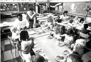 Staff and children are at mealtime in the CAW labour community childcare centre in Windsor. The Windsor Centre was opened in 1989 after the Canadian Auto Workers bargained with Chrysler, General Motors, and Ford for financial support for childcare centres. The intention was to provide quality, not-for-profit care to support parents and to act as a model for a genuine child care strategy.