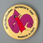 Button was used for the 1982 International Women's Day March in Toronto. The image of the woman waving a large flag links International Women's Day to early socialist celebrations.